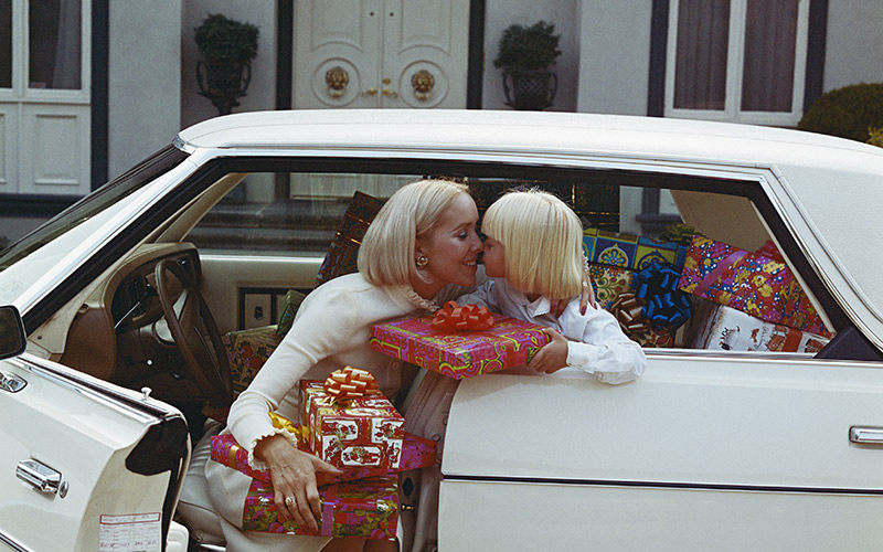 Bild i 70-tals stil med kvinna och barn i vit bil